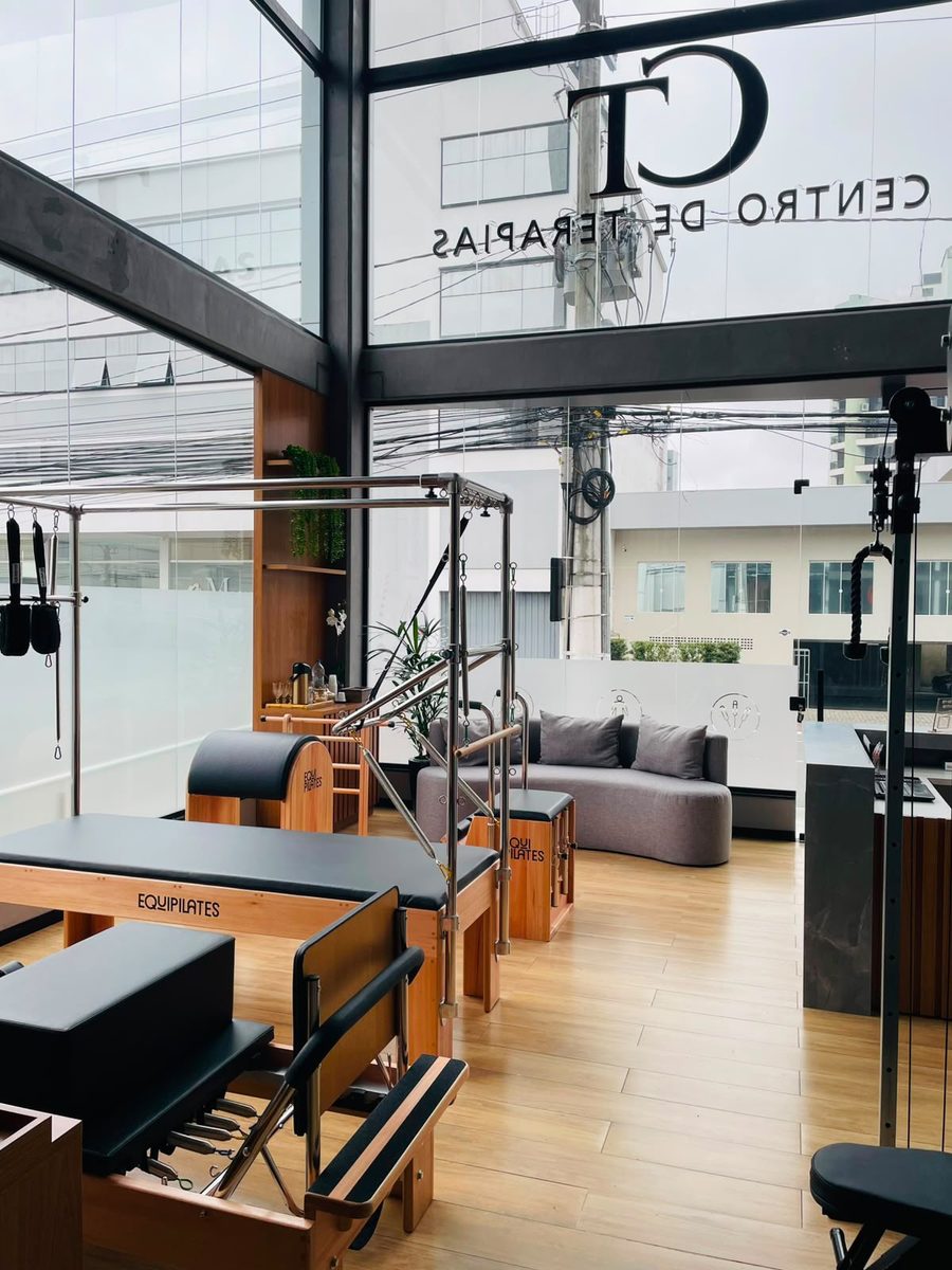 Área de pilates do Centro de Terapias vista pelo vidro, com a sala de espera ao fundo